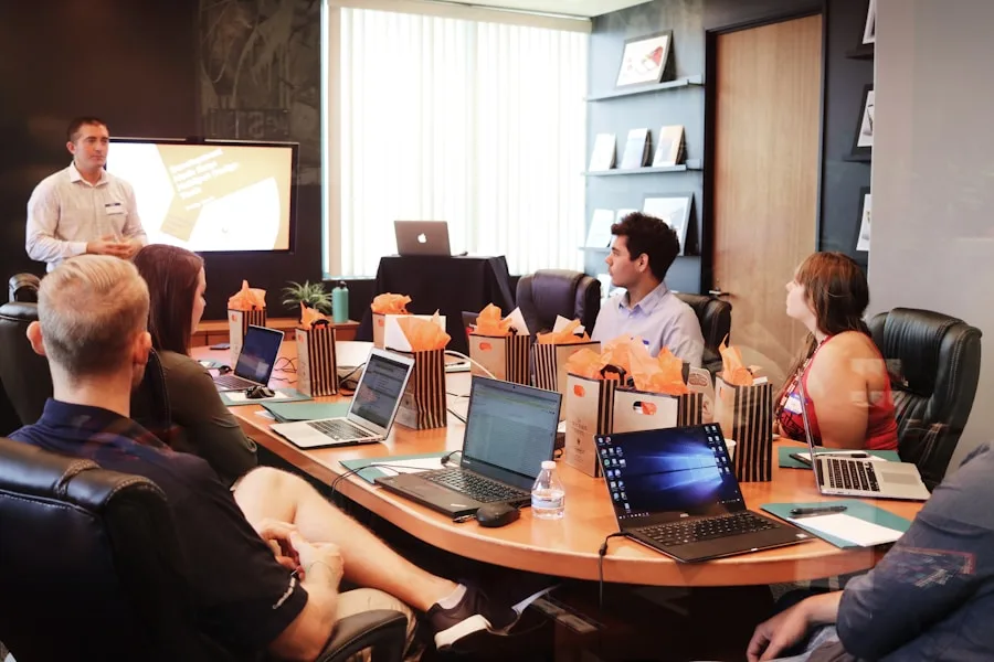 A business meeting is in progress around a wooden table, discussing creative arts projects.