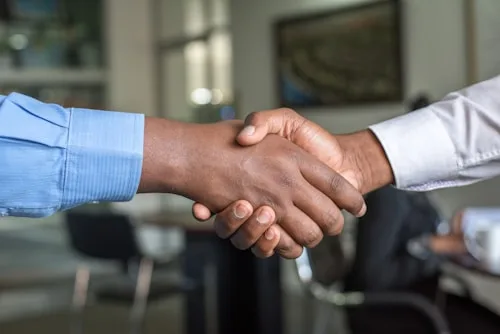 Two people shake hands during a business meeting, representing collaboration in creative arts.