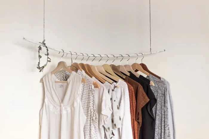 A clothing rack showcases neutral blouses and tops as part of creative arts training at CAQA Creative.