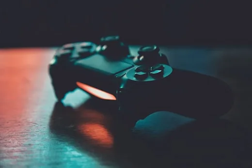 A black gaming controller sits on a surface with vibrant rgb lights, showcasing creative arts technology.