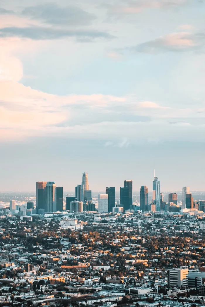 The Los Angeles skyline stretches across a cloudy urban landscape.
