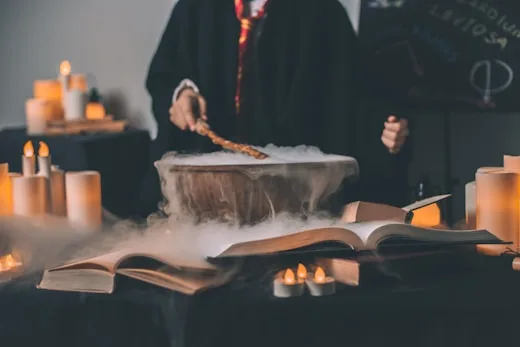 A cauldron bubbles with a potion as someone practices wizardry, showcasing creative arts.